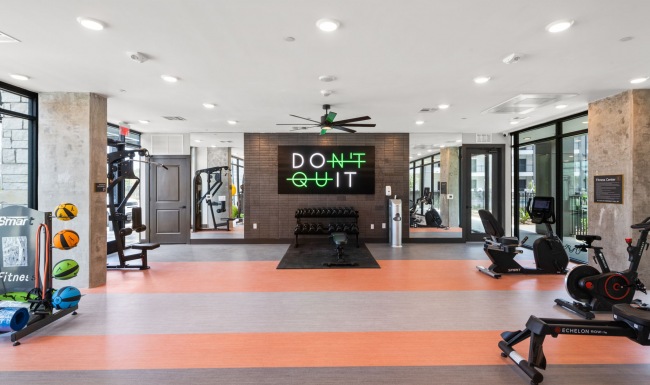 fitness center with a sign that says "dont quit", yoga balls, free weights, weighted machines, and stationary bikes